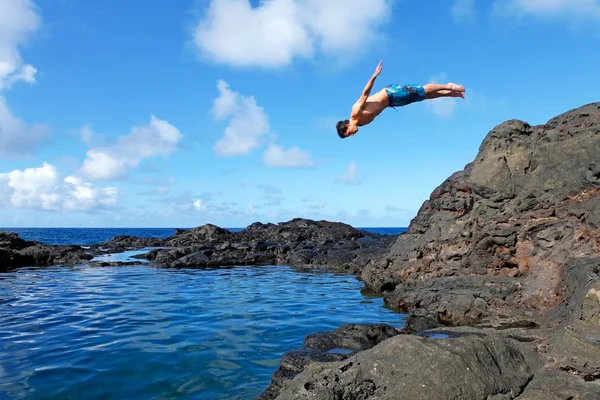 Jonge man springen van de klif in aan het water. — Stockfoto