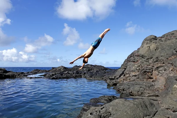 Genç adam su içinde uçurumdan atlama. — Stok fotoğraf