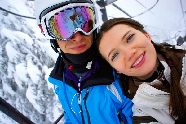 Young couple on the chair lift at the skiing resort. — Stock Photo, Image