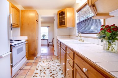 Oak cabinets kitchen with tile floor and flowers clipart