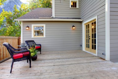 Deck with two chairs and fenced back yard near home exterior shot. clipart