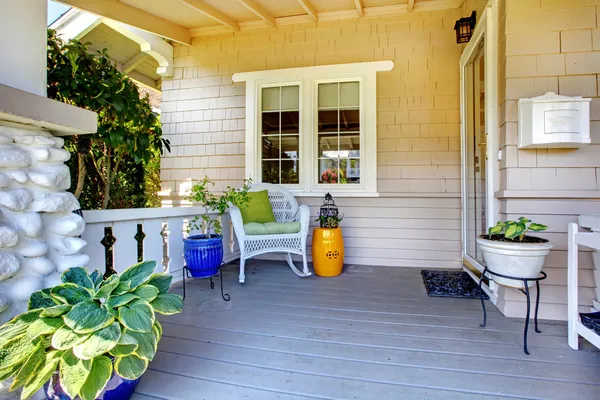 Covered entrance porch with plants and chair. — 图库照片