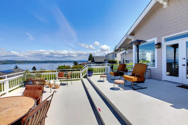 Grande terrasse de maison avec vue sur l'eau et meubles . — Photo