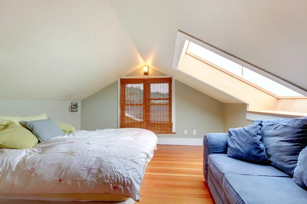 Tavan yatak odası ile yatak ve mavi koltuk — Stok fotoğraf