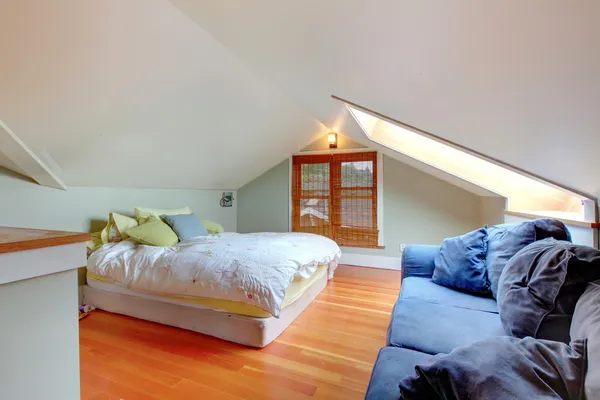 Мансардна спальня з ліжком і синім диваном — стокове фото