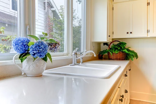 Fregadero de cocina con armarios blancos y flores . — Foto de Stock