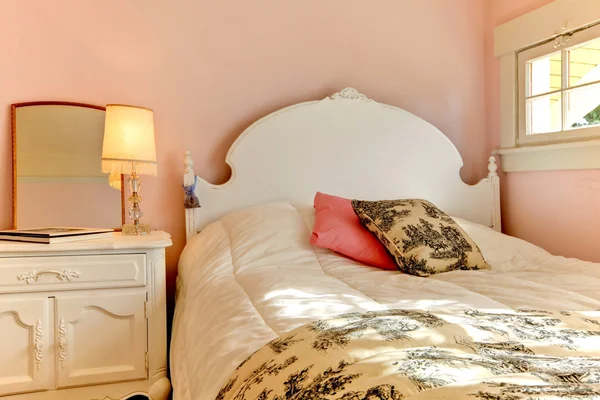 Chambre rose avec lit blanc et table de nuit . Photo De Stock