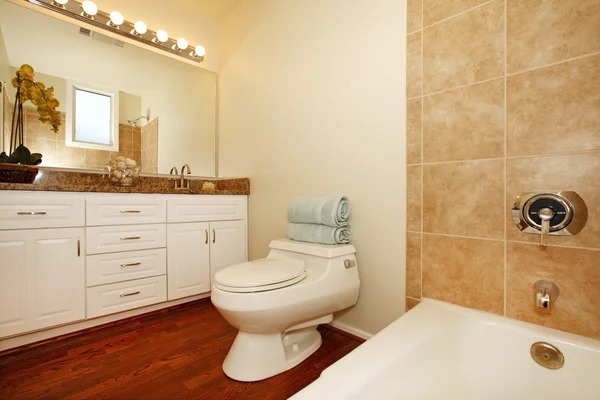 Μπάνιο με μπεζ κεραμικά πλακίδια και ξύλινο πάτωμα. — Φωτογραφία Αρχείου