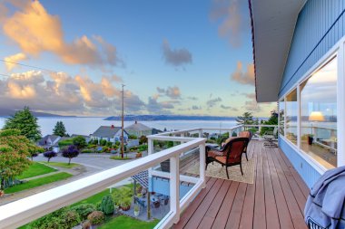 Mavi Ev koltukları ve su manzaralı geniş balkon.