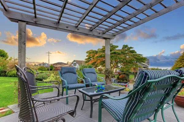 Solnedgång över trädgård lusthus med stolar. — Stockfoto