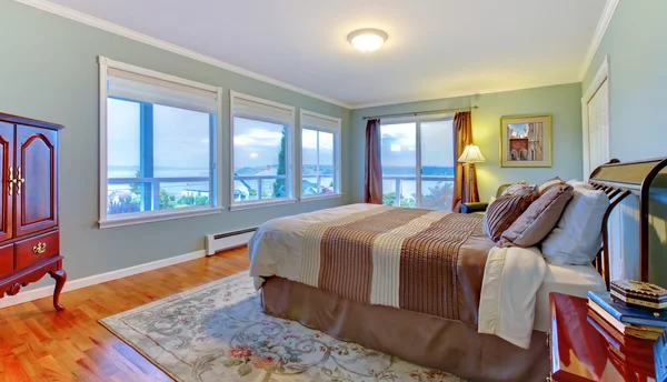 Grote groene slaapkamer met veel windowss en browns pedding. — Stockfoto