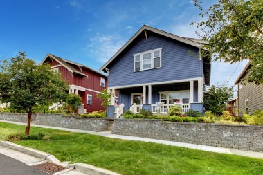 Blue house with stone wall and covered porch. clipart