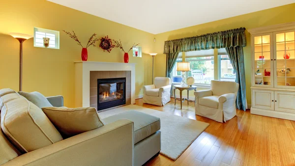 Obývací pokoj s krbem v měkké žluté a modré. — Stock fotografie