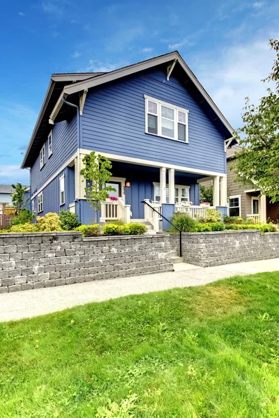 Modrý dům s kamennou zeď a krytá veranda. — Stock fotografie