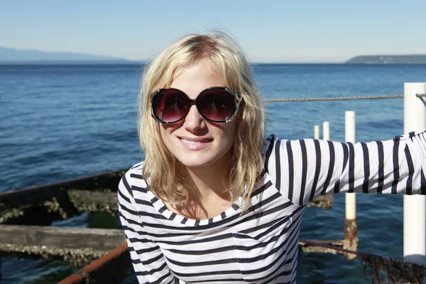 Blond beautiful girl near the sea in a stripe T-shirt. — Stock Photo, Image