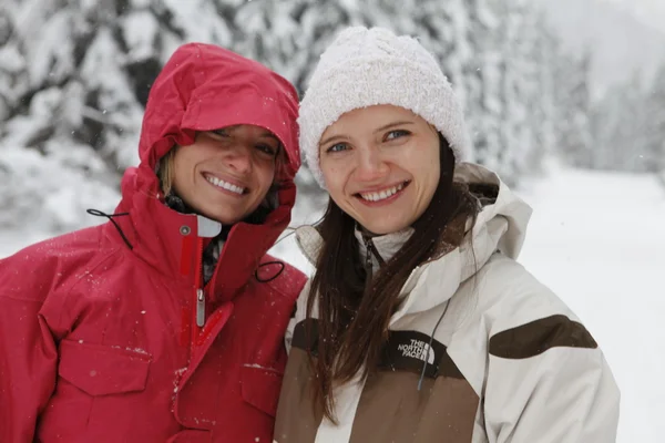 Dos jóvenes riendo felices mujeres en el bosque de nieve — Foto de Stock