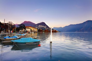 Lugano Gölü. İsviçre. İyi akşamlar. Tekneler ve downtown yakınındaki dağlarda.