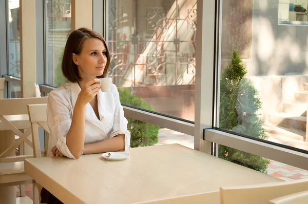 Das Mädchen im Café hinter einer Tasse Kaffee — Stockfoto