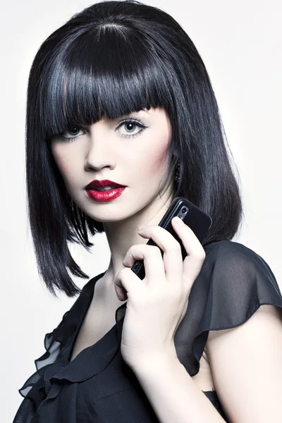 Vacker flicka med perfekt hud, rött läppstift och svart hår med telephon — Stockfoto