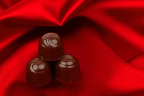 Caramelle al cioccolato su raso rosso — Foto Stock
