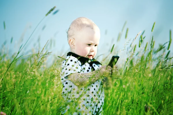 Chłopiec w trawie rozmowy przez telefon — Zdjęcie stockowe