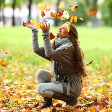 Woman drop leaves in autumn park clipart