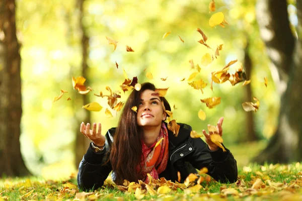 Kvinna droppe blad i höst park — Stockfoto