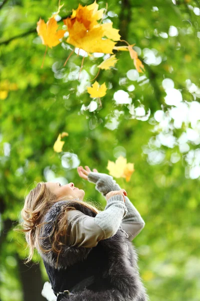 Žena drop listí v podzimním parku — Stock fotografie