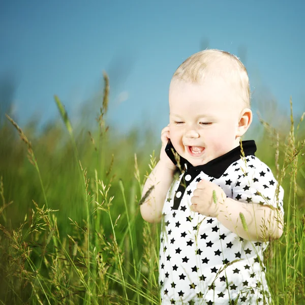 Niño en la hierba llamada por teléfono Imagen de archivo