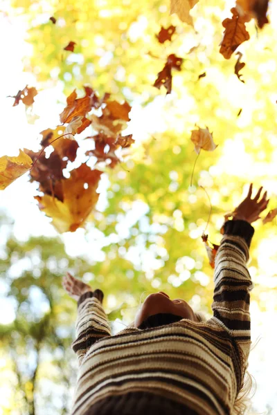 Vrouw drop bladeren in de herfst park — Stockfoto