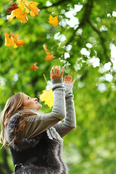Жінка кидає листя в осінній парк — стокове фото