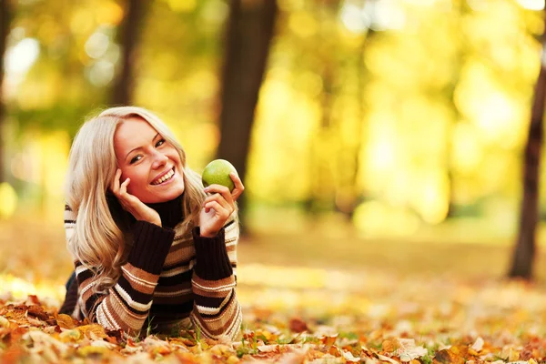 Γυναίκα φάτε μήλο στο πάρκο φθινόπωρο — Φωτογραφία Αρχείου