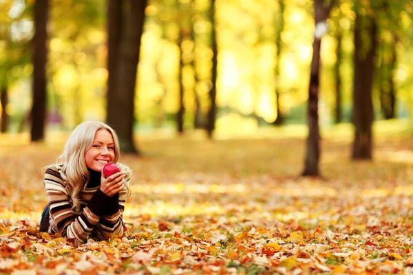 Femme manger des pommes dans le parc d'automne — Photo