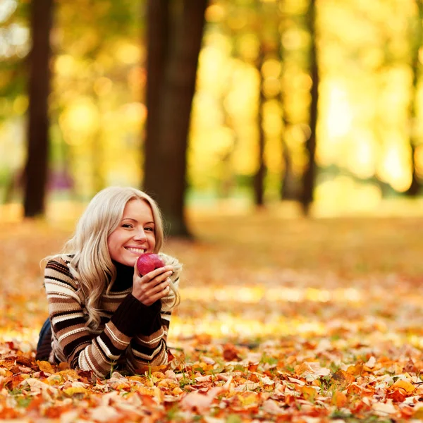 Γυναίκα φάτε μήλο στο πάρκο φθινόπωρο — Φωτογραφία Αρχείου
