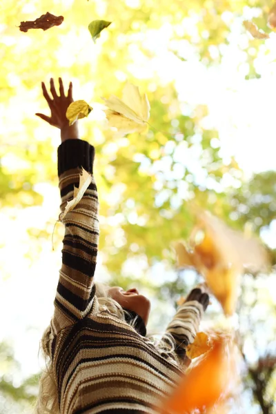 Жінка кидає листя в осінній парк — стокове фото