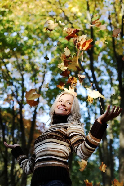 Donna foglie goccia nel parco autunnale — Foto Stock