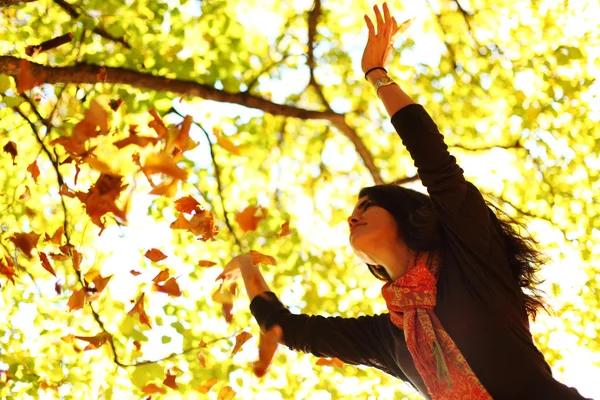 Vrouw drop bladeren in de herfst park — Stockfoto