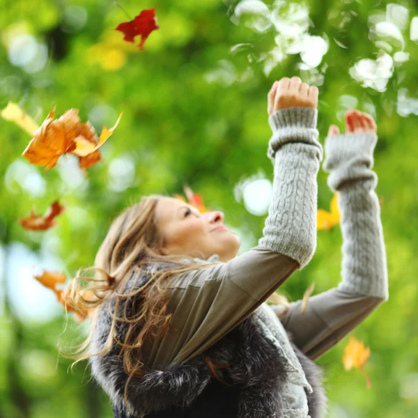 Женщина роняет листья в осеннем парке — стоковое фото