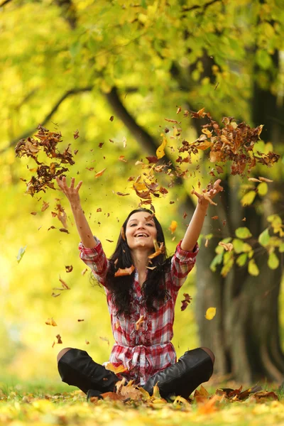 Femme goutte feuilles dans le parc d'automne Images De Stock Libres De Droits