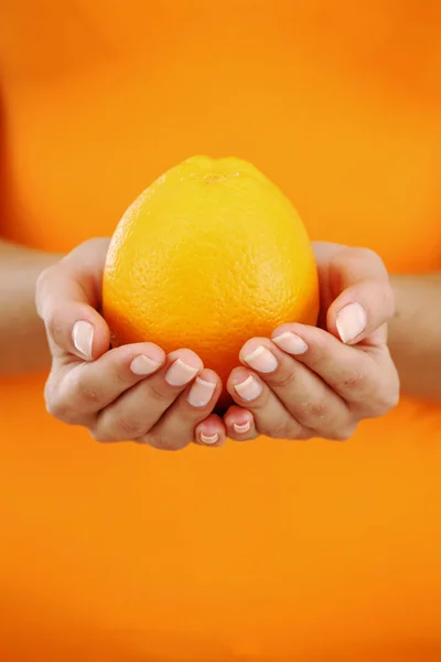 Оранжевый в женских руках — стоковое фото