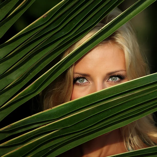 Vrouw achter de palmbladeren — Stockfoto