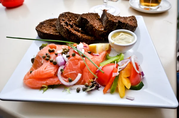 Stock image A dish of red salted fish with brown bread on a white square plate