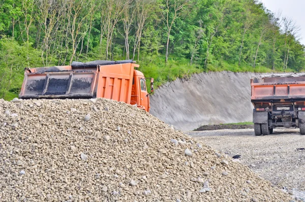 Pile of gravel and dump trucks — Stock Photo, Image