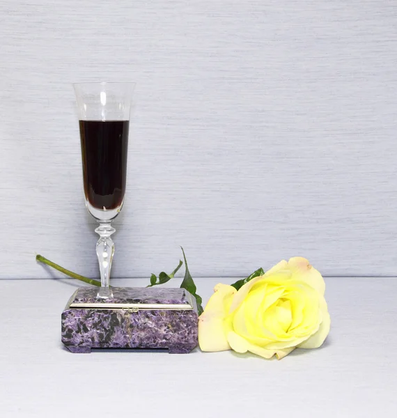 Ένα ποτήρι με κρασί, ένα cacket και ένα κίτρινο τριαντάφυλλο — Φωτογραφία Αρχείου