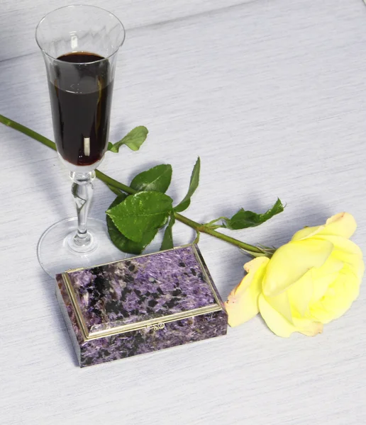 Ένα ποτήρι με κρασί, ένα cacket και ένα κίτρινο τριαντάφυλλο — Φωτογραφία Αρχείου