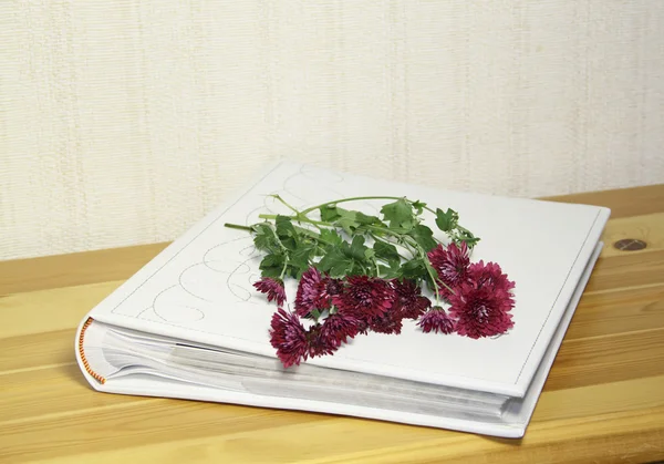El álbum fotográfico con flores de ramo sobre una mesa de madera —  Fotos de Stock