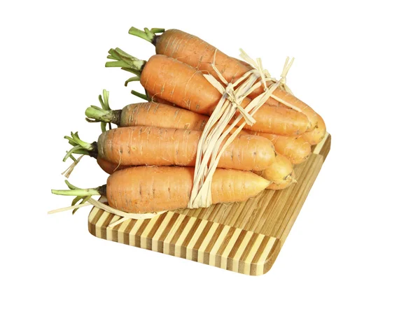 Las zanahorias frescas en una tabla de bambú sobre un fondo blanco — Foto de Stock