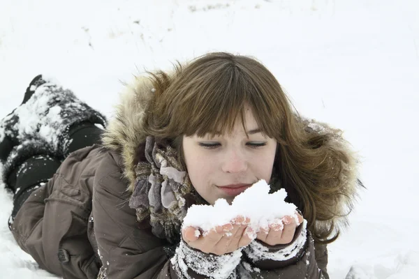 Das schöne Mädchen liegt mit Schnee in der Hand — Stockfoto