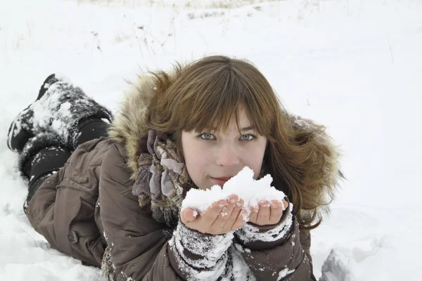 Das schöne Mädchen liegt mit Schnee in der Hand — Stockfoto