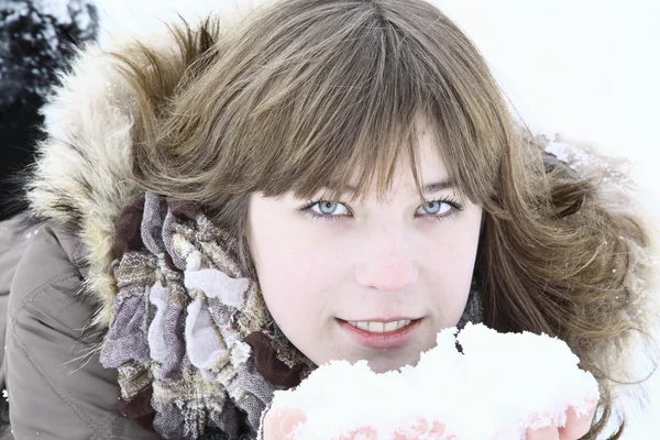 La hermosa chica se acuesta con nieve en las manos — Foto de Stock